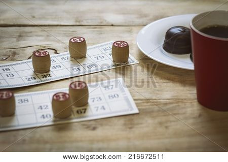 Cards And Chips For Playing Bingo On A Wooden Table. Cup With Coffee