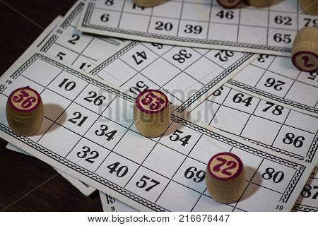On A Wooden Bingo Table Game, A Cup With A Coffee, A Biscuit And An Orange Slice