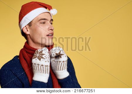 man in mittens looks at free space for copying, light yellow background, new year, christmas.