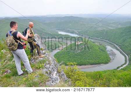 Hikers on top of a mountain enjoy the beautiful view of nature, forest and river in valley. View on meanders of Morava river  from Kablar, Serbia