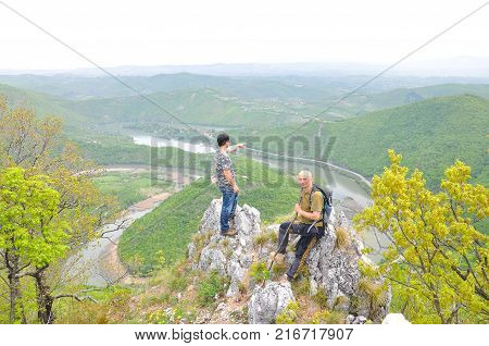 Hikers on top of a mountain enjoy the beautiful view of nature, forest and river in valley. View on meanders of Morava river  from Kablar, Serbia