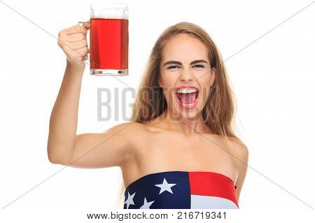 Young woman opening her mouth wide, blond, holding a glass of dark beer wrapped in an American flag, isolated on a white background