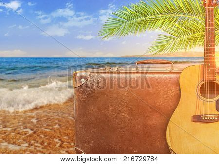 Concept of summer traveling with old suitcase and guitar and burning sun