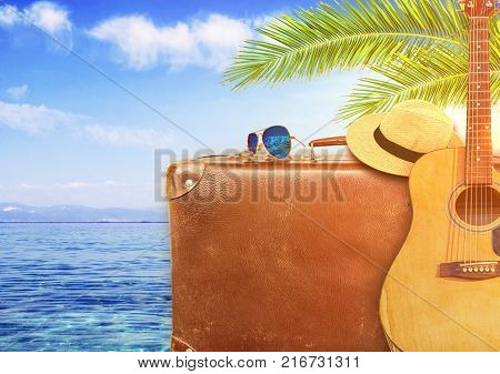 Concept of summer traveling with old suitcase and guitar and burning sun
