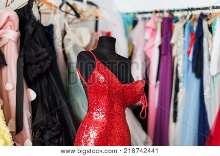Many ladies evening gown long dresses on hanger in the dress rent shop for the wedding day or photo session. Dresses rental concept. Selective focus. Ball gown rental concept