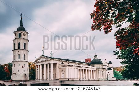 View Of old town center in VIlnius. Bell Tower and facade Of Cathedral Basilica Of St. Stanislaus And St. Vladislav On Cathedral Square. Famous Landmark in fall season under cloudy sky.