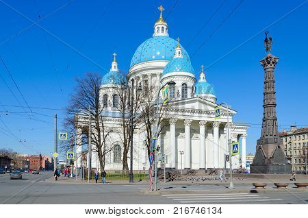 SAINT PETERSBURG RUSSIA - MAY 2 2017: Cathedral of Holy Life-Giving Trinity of Life Guards Izmailovsky Regiment (Troitse-Izmailovsky Cathedral) and Column of Glory. Unknown people walking down street