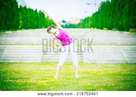 young woman jogging in the park, stretching