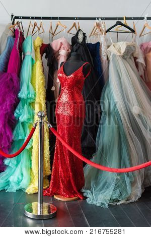 Many ladies evening gown long dresses on hanger in the dress rent shop for the wedding day or photo session. Dresses rental concept. Selective focus. Ball gown rental concept