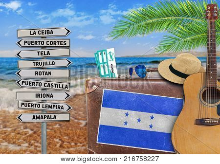 Concept of summer traveling with old suitcase and Honduras town sign