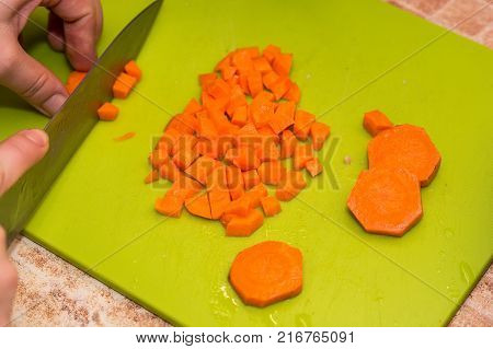 Closeup image of hands with knife cutting carrot