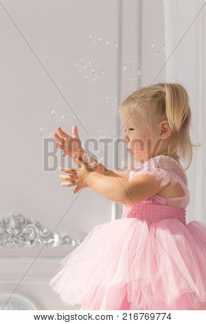 Beautiful Baby Girl in Dress is Catching Soap Bubbles