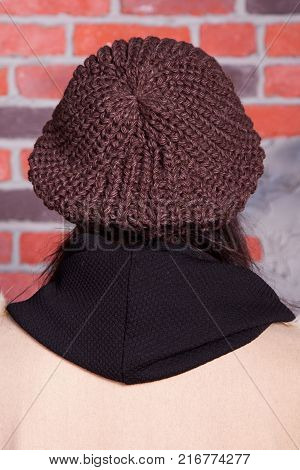 girl in hat and fur coat, against a brick wall background