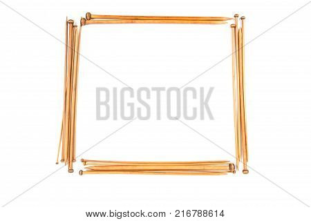 Wooden knitting needles arranged as borded frame isolated on white background