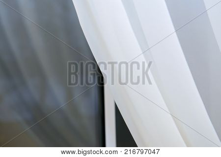 The window in the night covered with a white curtain. The delicate silk curtains at the window. Fabric curtained Windows.