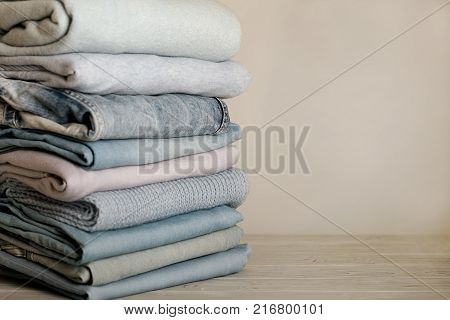 Pile of knitted clothes (sweaters scarves pullovers) blue white and grey colors. Selective focus.