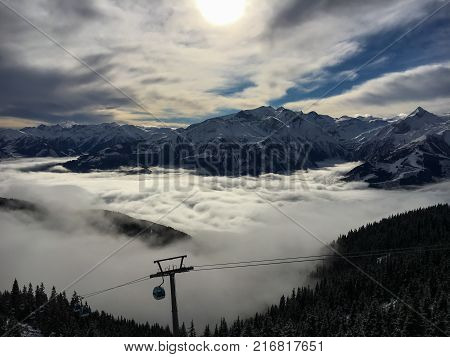 A blanket of clouds is lying over Lake Zell on a sunny winter day in the Austrian alps