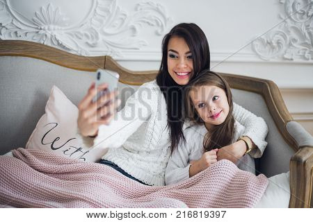Well-groomed hand of a woman holding a phone taking a selfie with her daughter, little girl.