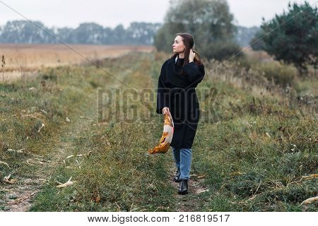 Young woman standing on road in coutryside. Autumn, cloudy weather.
