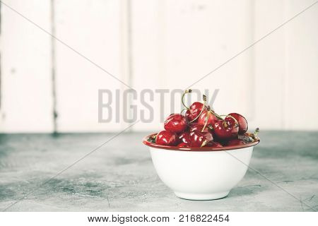 Fresh cherries in bowl on a rustick background