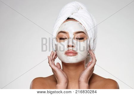 Portrait of beautiful lady with closed eyes and towel on her head put scrab on her face isolated