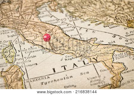 Italy vintage 1920s map with a red pushpin on Rome, digital painting effect applied