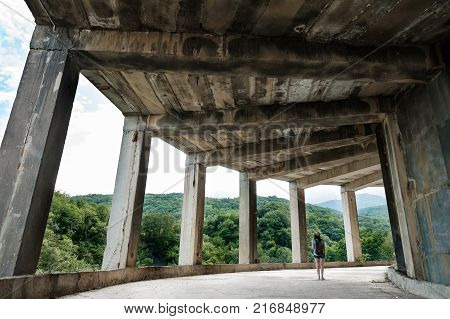 Traveling girl in a ruined abandoned building, looking at the sea