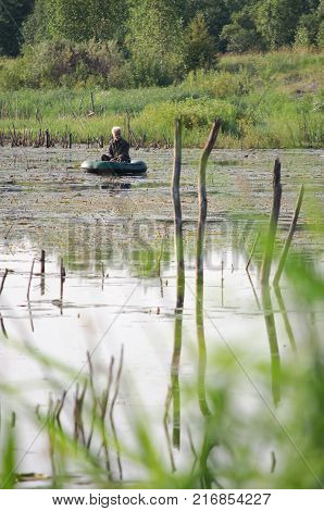 Vyazma, Russia - July 19, 2011: A fisherman in a rubber boat on a lake in central Russia