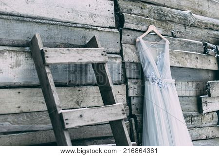 A Beautiful Dress Of Gray Hanging On A Hanger On A Wooden Background