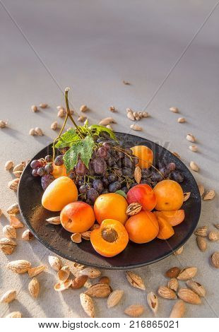 Fruit plate with grapes, apricot and almond on gray. Helthy food backround. Poster, magazine cover