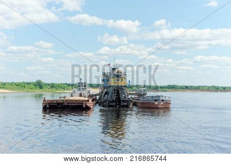 Volga, Russia. - June 2.2016. The floating dredger works deepens the bottom of the Volga River. Next to it is a barge loaded with sand and a river tugboat named ShS 11.