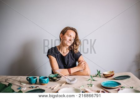 potter, tools, ceramics art concept - handsome young brunette female smiling.