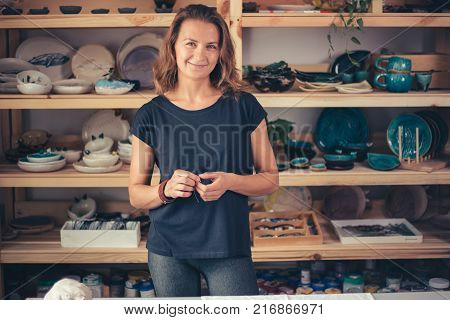 potter, tools, ceramics art concept - handsome young brunette female smiling.