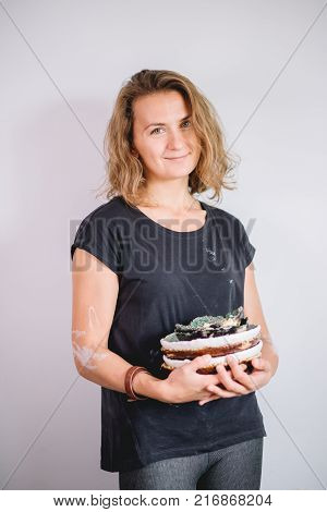 potter, tools, ceramics art concept - handsome young brunette female stand with finished utensils, smiling ceramist at workplace with baked cups and jugs at background