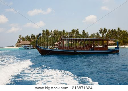 Maldivian dhoni in front of the turquoise bay and island