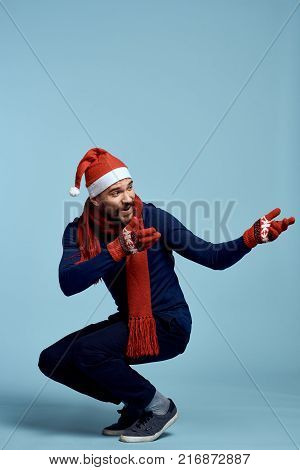 man crouched, light blue background, free space for copy, new year, christmas, holiday.