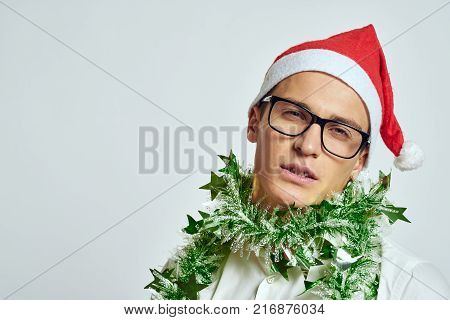 man in glasses with tinsel on his neck, portrait, light background, free space for copy, new year.