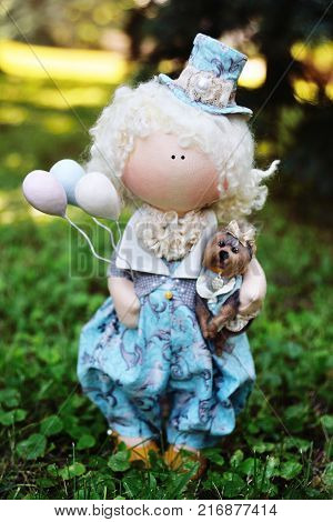 A handmade doll holds balloons and a small dog. Nostalgia, magic, kindness, childhood, dreams