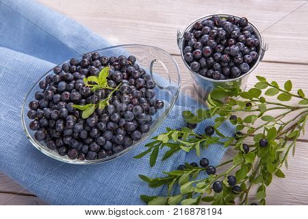 Fresh forest berry, blueberries in a glass plate on a wooden table.