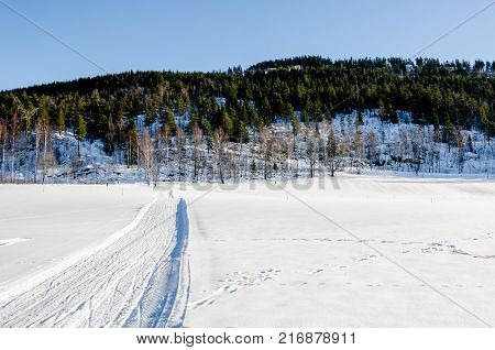Road path and ski tracks on the frozen lake of Bogstadvannet in Oslo, Norway. Inspirational peace