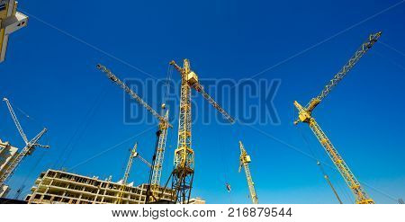 Large construction cranes. High and heavy construction machinery. Construction of  houses. Urbanization is the process of urban growth.