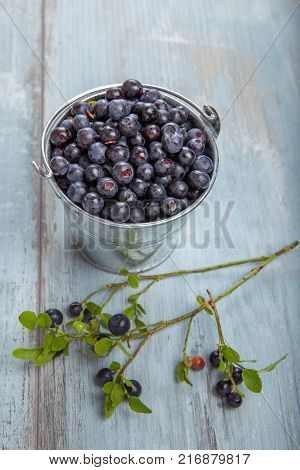Fresh forest berry, blueberries in a glass plate on a wooden table.