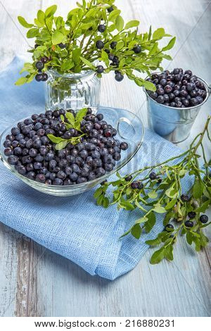 Fresh forest berry, blueberries in a glass plate on a wooden table.
