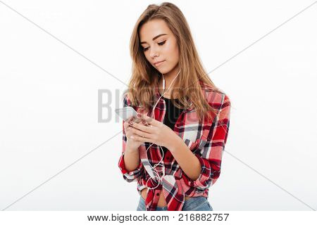 Portrait of a lovely pretty girl in plaid shirt texting on mobile phone isolated over white background