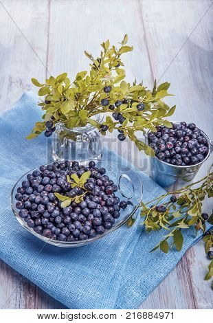 Fresh forest berry, blueberries in a glass plate on a wooden table.