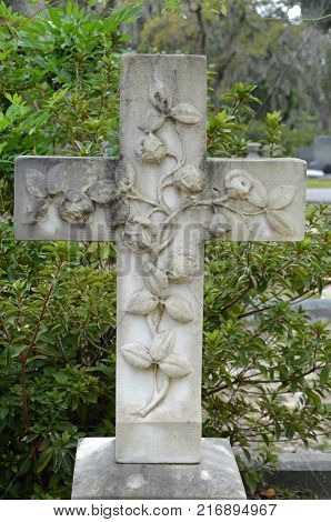 THUNDERBOLT, GA - October 8, 2017 A cross monument adorned with roses rises into the Southern flora of Bonaventure Cemetery.