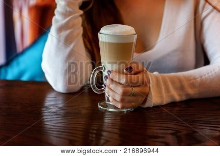 Latte macchiato in tall glass close up. Coffee on a table in cafe
