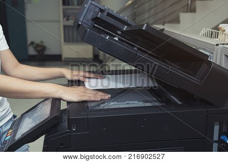woman hand putting a sheet of paper into a copying device