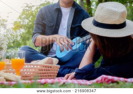 Picnic concept. Happy young asian friends having fun while eating and drinking at a picnic. Enjoying outdoor picnic in garden.