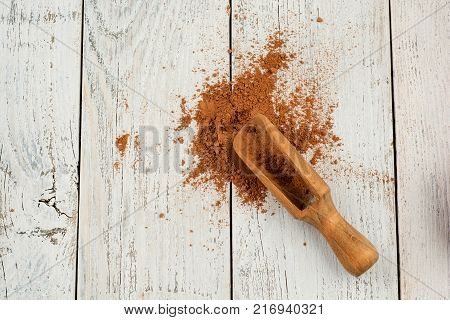 Cocoa powder on white rustic background, top view. Flat lay.